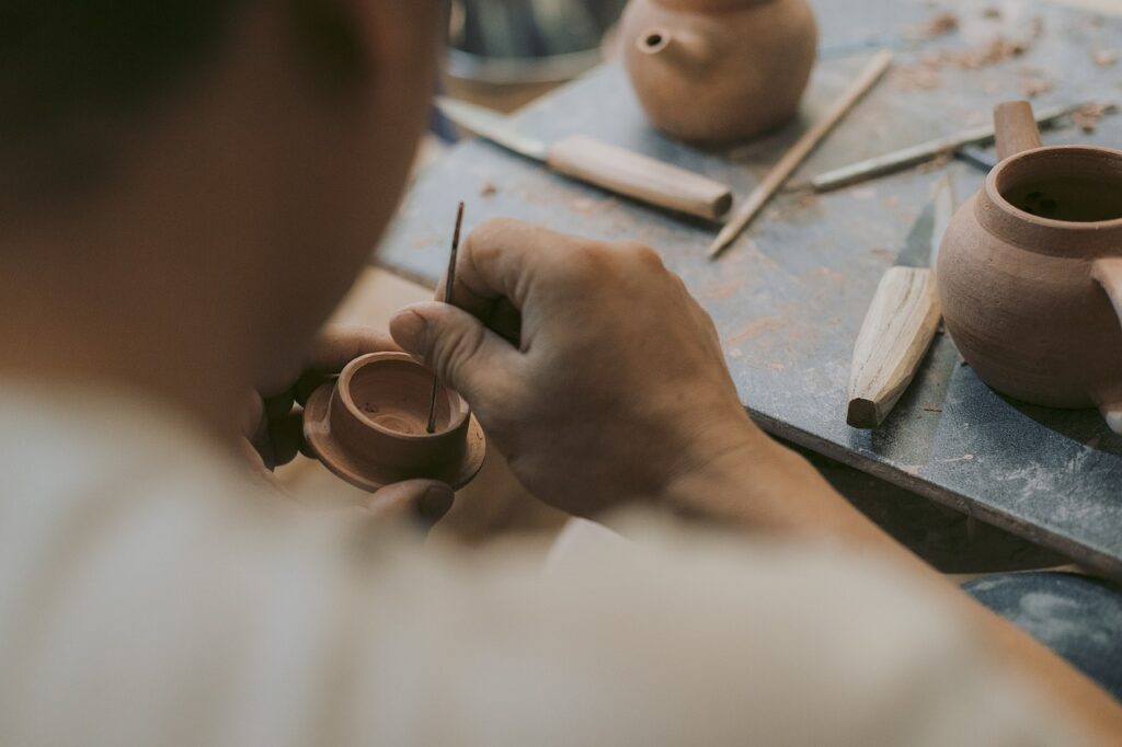 ceramist working on a cup on a table with tools for responsible consumption