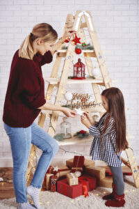 Mother and daughter decorating the christmas tree that is a ladder